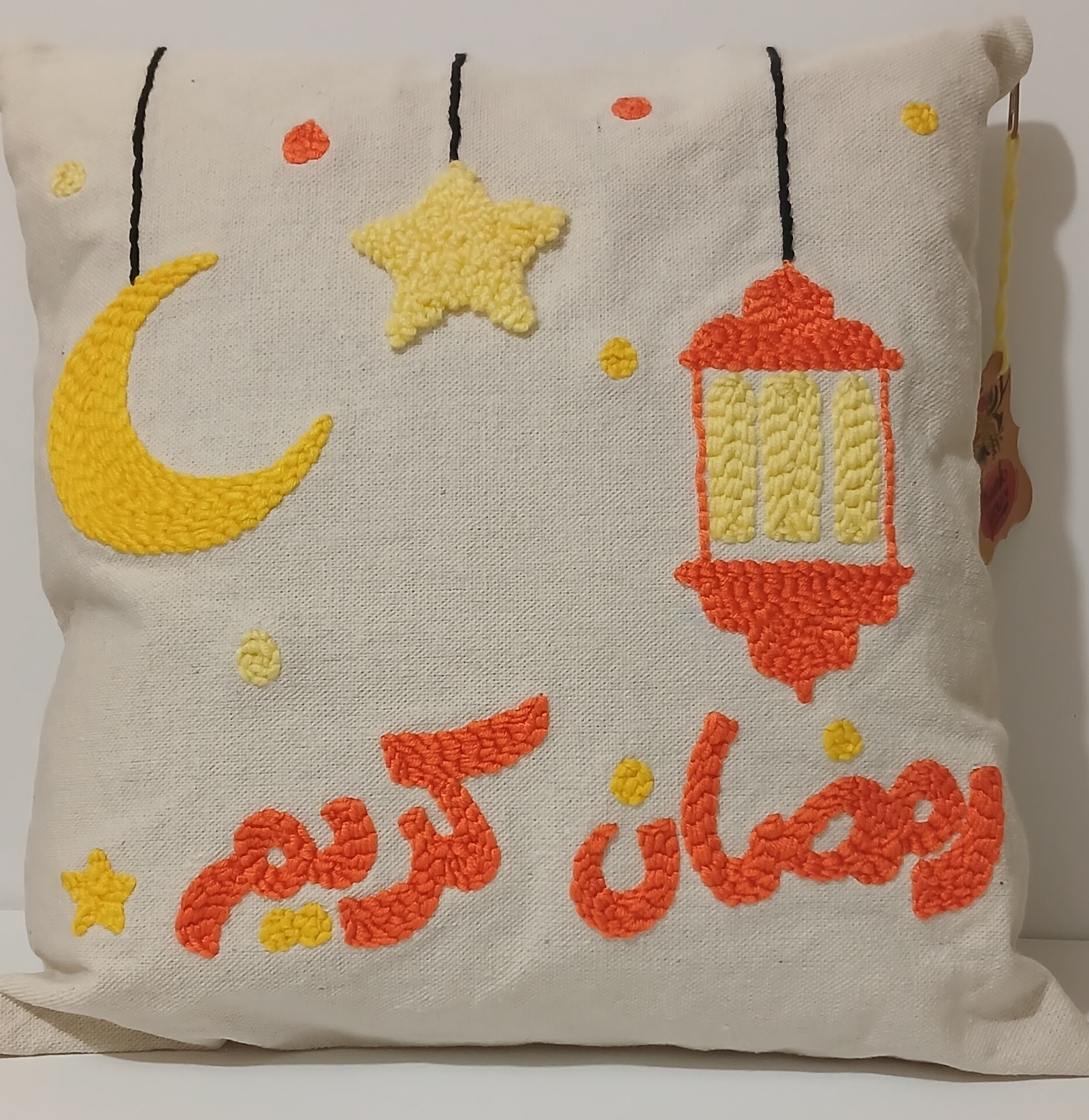 White punch needle cushion with a yellow crescent, orange lantern and Ramadan Kareem lettering